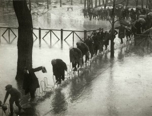 Žmonės mėgina kėdėmis pereiti Mezon Lafito hipodromą Senos potvynio metu. Paryžius. 1924