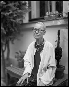 Dovilė Dagienė-DoDA. Menininkė Aleksandra Jacovskytė sodelyje prie savo namų. Iš ciklo „Portretas prisiminimui“. Vilnius, 2025